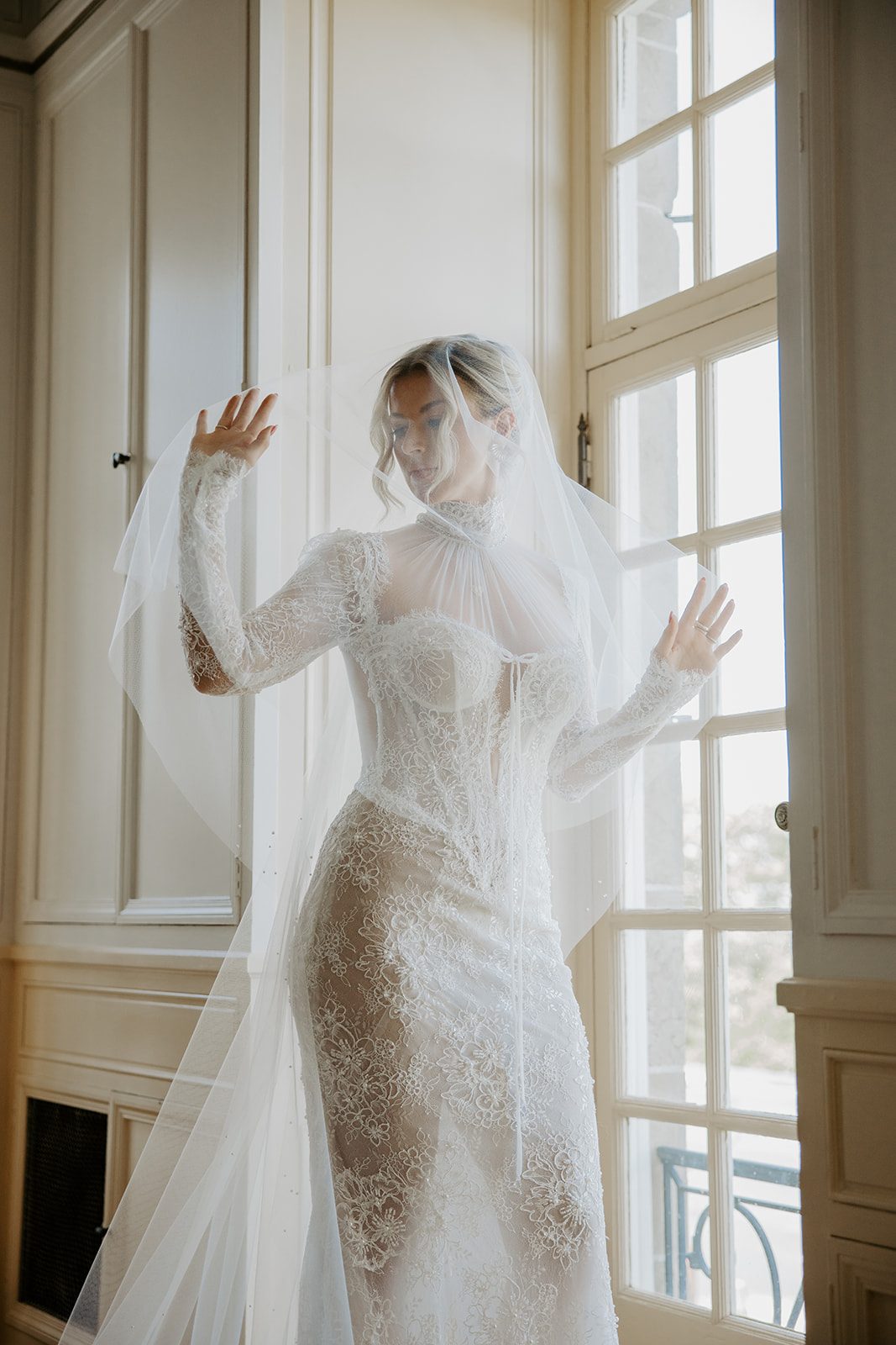 Anne in her lace gown and veil by a tall window at Glen Manor House, Portsmouth RI