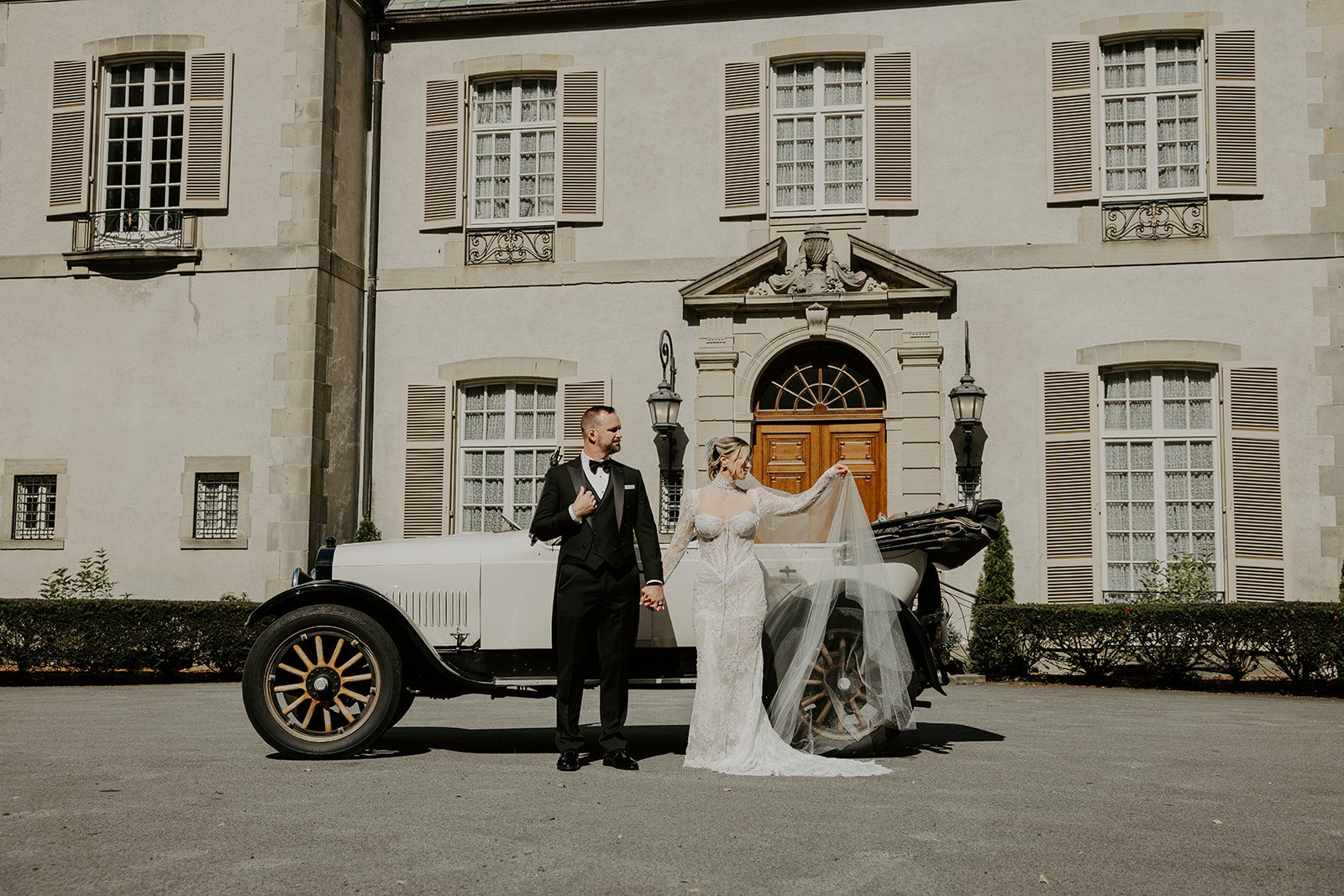 Jim and Anne holding hands beside a vintage car in front of Glen Manor House, Portsmouth RI